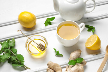 Cup of ginger tea and bowl with honey on white background
