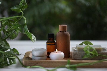 Beautiful composition with different spa products and green leaves on white table, closeup