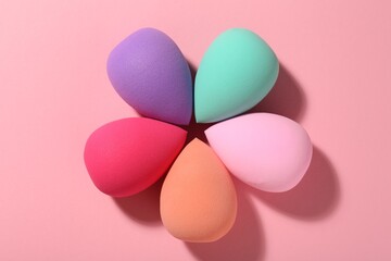 Many different makeup sponges on pink background, top view
