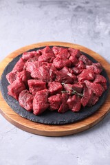 Pieces of raw beef meat and thyme sprigs on grey textured table