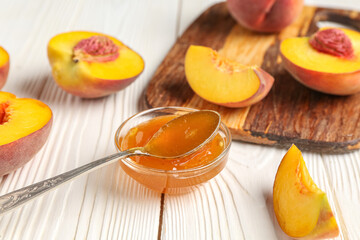 Bowl of sweet peach jam and fresh fruits on light wooden background, closeup