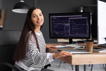 Pretty young female programmer with laptop in office