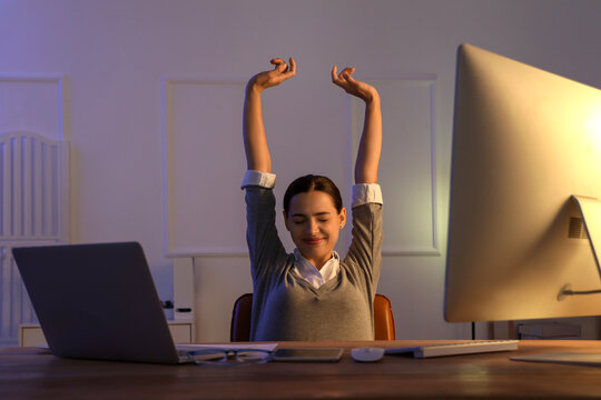 Pretty young female programmer stretching in office at night
