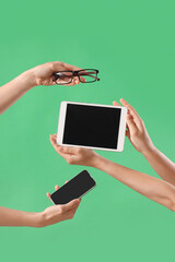 Women with tablet computer, mobile phone and eyeglasses on green background