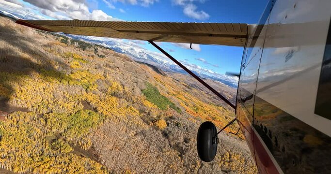 Airplane pov shot of wing flying through scenic mountains 
