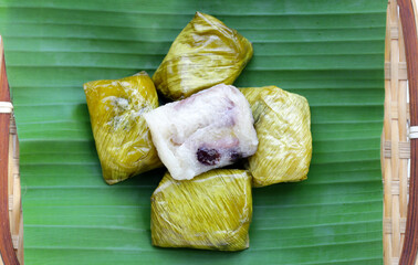 Bundled boiled sticky rice with banana and black beans wrapped in banana leaves