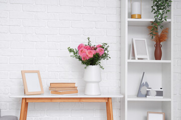 Vase of beautiful pink dahlias with books and frame on table in living room