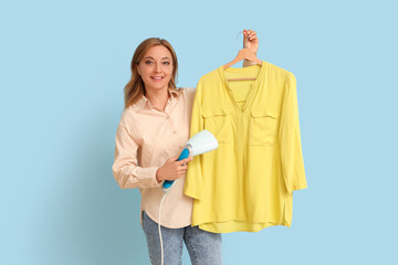 Mature woman with steamer and shirt on blue background