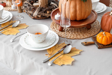 Festive table setting with autumn leaves and pumpkins, closeup
