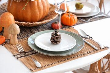 Autumn table setting with fir cone in kitchen, closeup