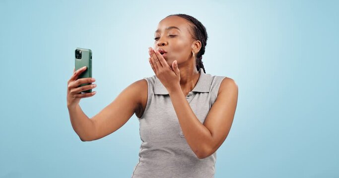 Peace, selfie and black woman with kiss, tongue out and hand gesture on studio on blue background. Smartphone, profile picture and female influencer with face emoji for social media, blog or podcast