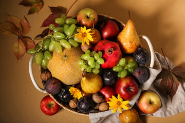 Wicker basket with different fresh fruits on beige background