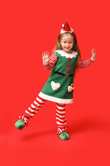 Cute little girl in Christmas elf costume on red background