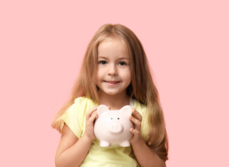 Fototapeta na wymiar Cute little girl with piggy bank on pink background