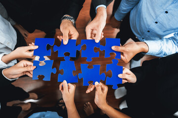 Top view multiethnic business people holding jigsaw pieces and merge them together as effective...