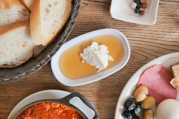 butter cream and honey in a bowl with olive, salami and bread on table 