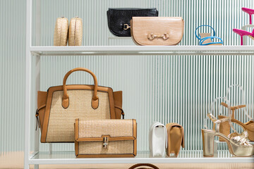 An assortment of shoes and handbags are seen displayed on a white shelving unit in a trendy retail...