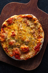 A freshly made wood-fired Margherita pizza rests on a wooden chopping board.