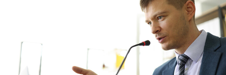 Focused manager speaks in microphone at online seminar