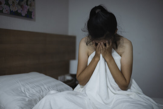 Woman covering face with hands while lying on bed at home. The concept of sexual harassment against women and rape. human trafficking. International Day for the Elimination of Violence against Women.