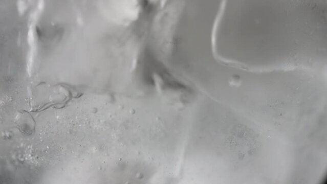 Close-up of water being poured into an ice-filled glass: A refreshing visual feast. The clear liquid flows gracefully over ice, creating a mesmerizing tableau of chilled. High quality 4k footage