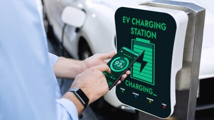 Businessman holding smartphone display battery status interface by smart EV mobile application...