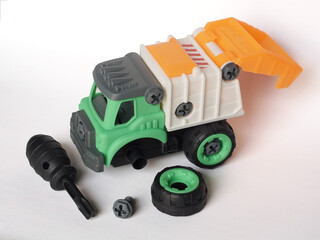 Fototapeta premium DIY plastic garbage truck toy with tire apart isolated on white background with screwdriver and bolt.