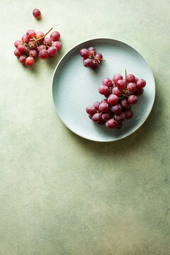Red grapes on a blue plate. Food background with space for text.