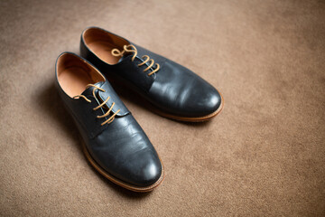 Grooms black coloured leather shoes on carpeted floor