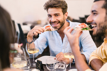 Dining experience with gourmet pizza and wine - group of young people relish a gourmet pizza in a...