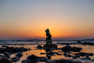 Stone balance on the beach at sunset. Pyramid of the small pebbles on the beach.