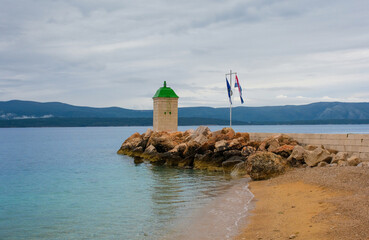 The pier and harbour lighthouse on the waterfront of Bol town on Brac Island, Croatia