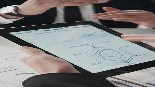 Vertical closeup of unrecognisable businessmans hands holding tablet and scrolling information about leadership cohesion perspectives in office during discussion meeting