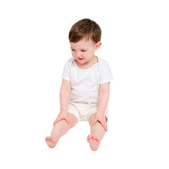 A happy baby is sitting on a studio, isolated on white background. Full-length portrait of a smiling child, isolated on white background. Kid aged about two years (one year nine months)