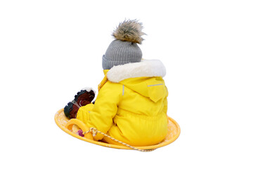 Happy toddler baby rides on an ice sled in the snow in a yellow snowsuit, isolated on white...