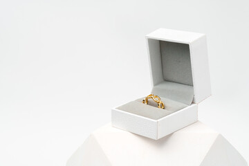 Golden ring in white jewelry box on white background studio shot