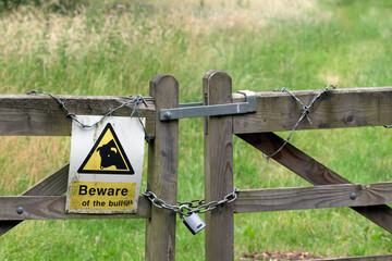 Locked gate to field with beware of bull sign.