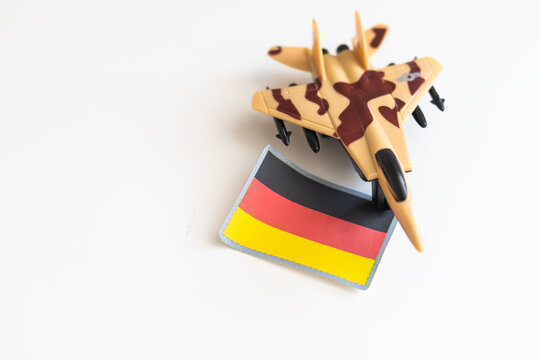 War, military threat, military power concept. Germany. Plane toy near German flag on grey background top view space for text