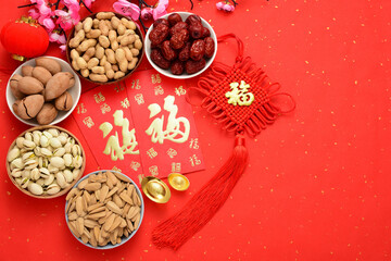 Obraz na płótnie Canvas On the red background of the Chinese New Year, there are nut snacks, red envelopes, ingots, preserved plums, and lanterns. The Chinese meaning in the picture is: good luck