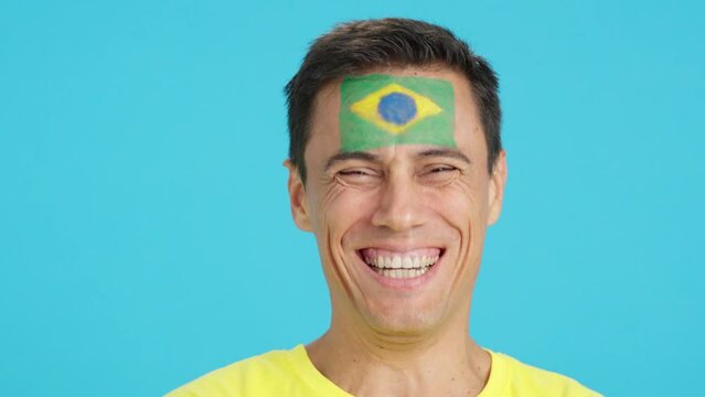 Man with a brazilian flag painted on the face smiling