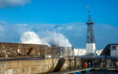 Obraz premium Storm hitting the coast of Scotland with crashing waves coming over a harbour wall