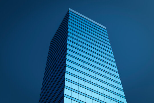 High-rise modern building made of blue glass against the sky.