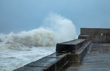 Fototapeta na wymiar Storm hitting the coast of Scotland with crashing waves coming over a harbour wall