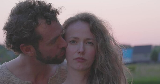 A romantic and sensual moment as a young hetero Caucasian millennial couple passionately embraces, kisses, and enjoys the warm embrace of a sunset backdrop, capturing the essence of love and