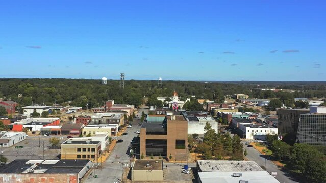Aerial view of historic buildings in Tupelo, Mississippi. The camera dollies left to reveal more of the city. United States and Mississippi flags wave on top of a building. 