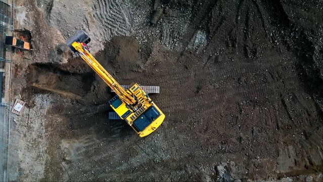 Static aerial top down view of excavator rotating on tracks in construction site