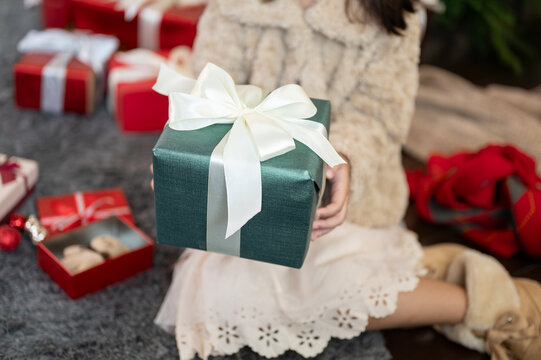 A cute young girl in a cute dress is holding a Christmas present gift box. close-up image