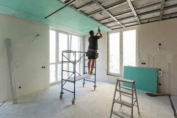 Man assembles profile metal frame for plasterboard ceilings