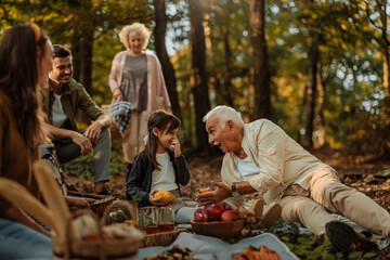 Whole happy Caucasian family having a picnic in the forest and having fun