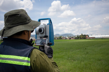 unrecognizable hispanic land surveyor engineer measuring a field using a theodolite surveying...